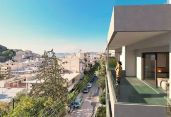 Person standing on a private luxury apartment balcony in Galatsi, featuring glass railings and a stunning panoramic view of the urban landscape and Veikou Hill.