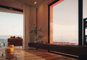 The perfect evening retreat. Project: Ikarou 7 | Developer: Thekla Constructions. Luxury living room interior in Alimos during sunset featuring a smart TV with Netflix warm ambient lighting wooden textures and a large window overlooking the city and sea by Thekla Constructions