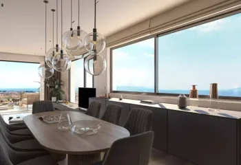 A Masterclass in coastal interior design. Project: Ikarou 7 | Developer: Thekla Constructions. Luxury dining room in Alimos with an oval wooden table gray modern chairs glass globe chandeliers and large windows overlooking the sea by Thekla Constructions