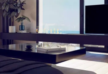 Atmospheric details that redefine luxury. Project: Ikarou 7 | Developer: Thekla Constructions. Close up of a modern glass ethanol fireplace on a dark minimalist shelf with a coffee table and sea view in a luxury Alimos penthouse by Thekla Constructions