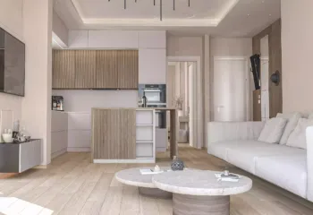 Interior 3D architectural rendering of a renovated penthouse in Pasalimani Piraeus, showcasing the open-plan connection between the modern living room and the kitchen island.
