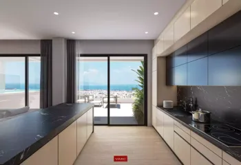 Culinary excellence with a view | The minimalist kitchen at Amerikis 2. Interior 3D rendering of a luxury minimalist kitchen in Ano Glyfada, featuring dark marble countertops, sleek black cabinetry, and an open view to the terrace and sea.