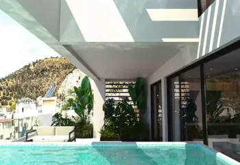 Architectural shadows and poolside serenity at Amerikis 2, Ano Glyfada. Exterior 3D rendering of a modern pergola design over a private infinity pool at a luxury penthouse in Ano Glyfada, featuring lush greenery and architectural shadows.