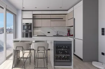 The heart of the Palaio Faliro Loft: a custom-designed kitchen featuring premium wood finishes, marble surfaces, and a professional-grade integrated wine fridge. High-end kitchen design with marble island and integrated wine cooler in Palaio Faliro Loft